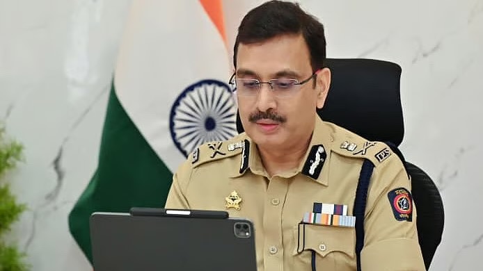 Vinoy Kumar Choubey working at his desk with a tablet, the national flag behind him.
