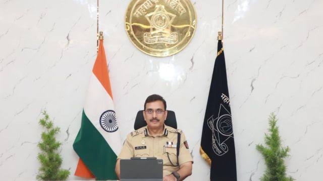 Vinoy Kumar Choubey seated at the commissioner's desk between the national flag and the Maharashtra Police standard.