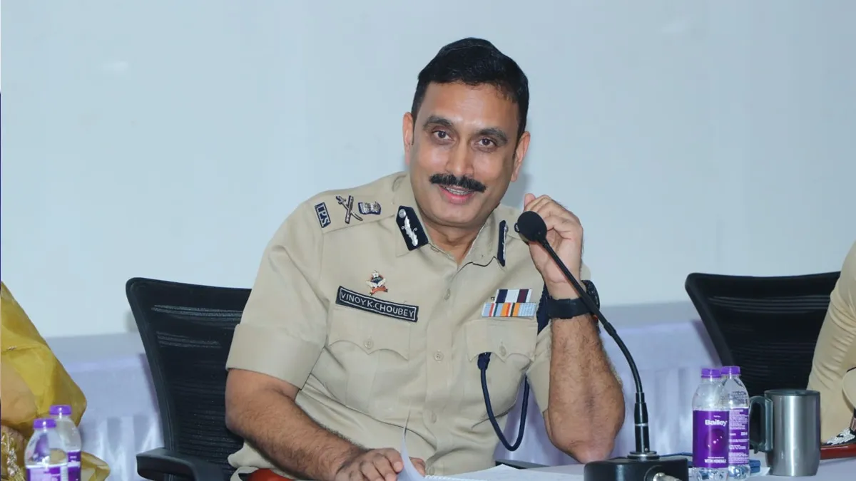 Vinoy Kumar Choubey speaking at a microphone during a public briefing, his name plate visible on the uniform.